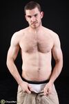 Dark-haired gay model Vander unveils his big hairy cock as he strips